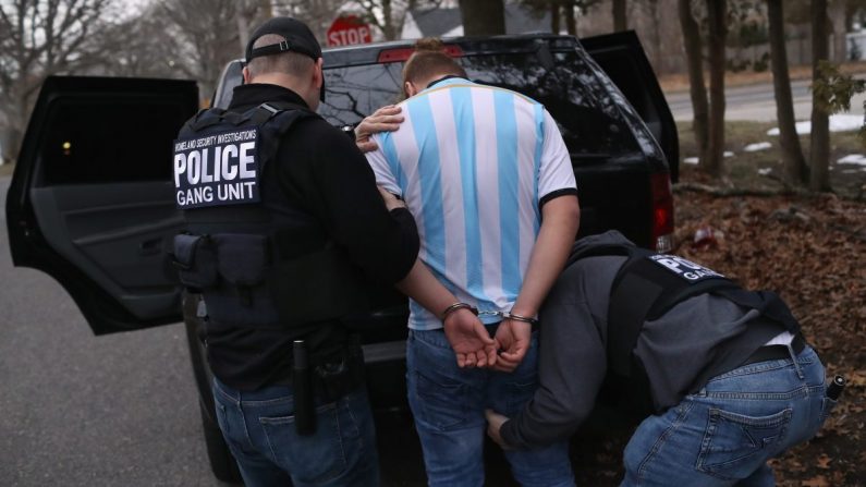 Agentes de Investigaciones de Seguridad Nacional de ICE registran a un presunto miembro de la pandilla MS-13 y a un inmigrante hondureño después de arrestarlo en su casa en Brentwood, Nueva York, el 29 de marzo de 2018. (John Moore/Getty Images)