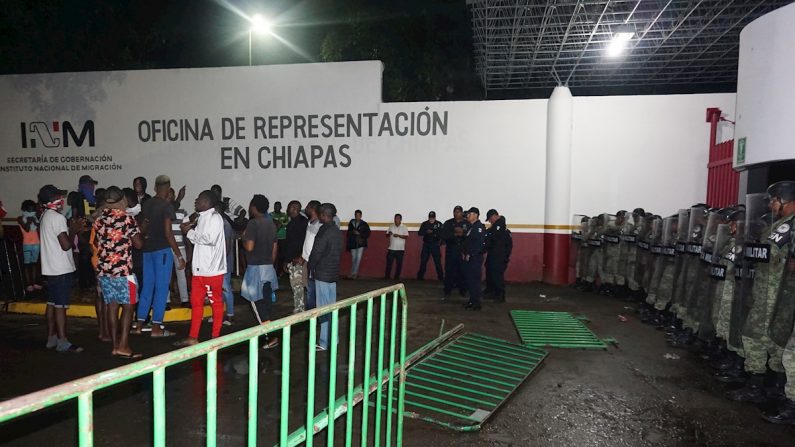 Migrantes de origen africano protestan ante la vigilancia de policías militares en la madrugada del 3 de octubre de 2019, en la garita Siglo XXI de la ciudad de Tapachula, estado de Chiapas (México). EFE/Juan Manuel Blanco
