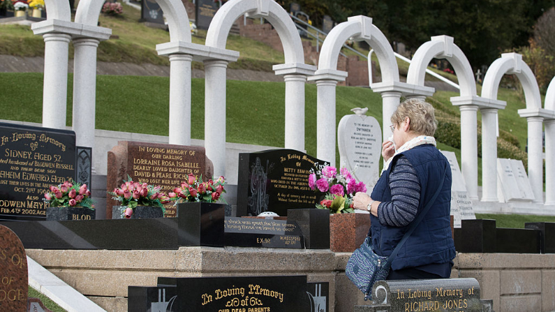 Personas en las tumbas de las víctimas del desastre de Aberfan en el 50 aniversario de la tragedia el 13 de octubre de 2016 en Aberfan, Gales. (Matt Cardy / Getty Images)