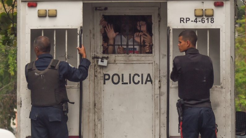 Policiais de Chávez transportam prisioneiros sobreviventes de um incêndio em celas de detenção policial em Valência, estado de Carabobo Norte, Venezuela, em 29 de março de 2018 (JUAN BARRETO / AFP / Getty Images)