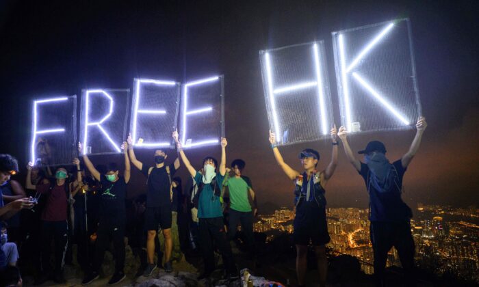 Activistas prodemocracia sostienen carteles iluminados por luces LED que dicen "HK libre" mientras forman una cadena humana en Lion Rock en Hong Kong, el 13 de septiembre de 2019.  (Anthony Wallace/AFP vía Getty Images)
