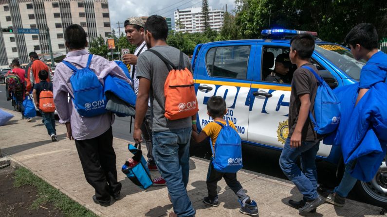 Familias pasan junto a un vehículo policial guatemalteco después de llegar en un vuelo de deportación de ICE desde los Estados Unidos el 22 de agosto de 2019 en la Ciudad de Guatemala, Guatemala. (John Moore/Getty Images)