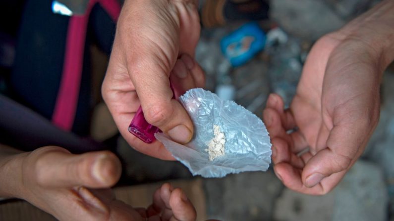 Un adicto sostiene una envoltura de plástico que contiene heroína en polvo en una posición en cuclillas detrás de una estación de policía en la ciudad marroquí de M'diq, cerca de Tetuán, el 14 de septiembre de 2019. (FADEL SENNA/AFP via Getty Images)