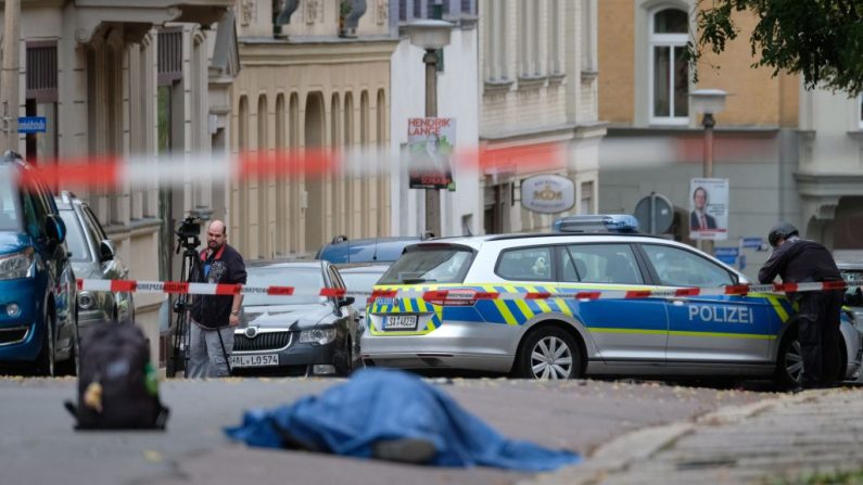 Un cuerpo tendido en la calle está cubierto mientras la policía bloquea el área alrededor del sitio de un tiroteo en Halle an der Saale, este de Alemania, el 9 de octubre de 2019. - Al menos dos personas murieron en un tiroteo en una calle en Alemania ciudad de Halle, dijo la policía, y agregó que los perpetradores estaban huyendo. (SEBASTIAN WILLNOW / dpa / AFP a través de Getty Images)
