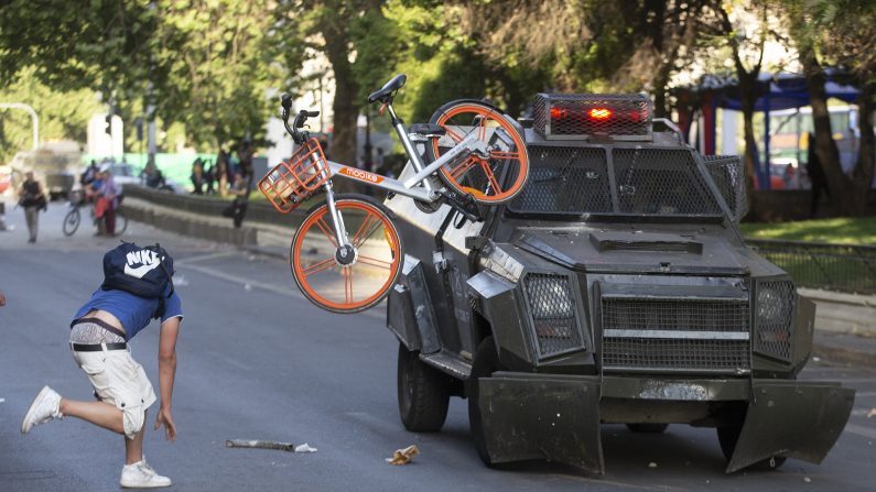Los manifestantes se enfrentan con la policía antidisturbios después de una protesta masiva de evasión de tarifas en el centro de Santiago, el 18 de octubre de 2019. (Claudio Reyes/AFP a través de Getty Images)