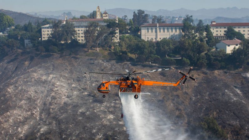 Helicóptero deja caer agua sobre las casas mientras el fuego de Getty arde en el área de Brentwood, California, el 28 de octubre de 2019. (APU GOMES/AFP via Getty Images)
