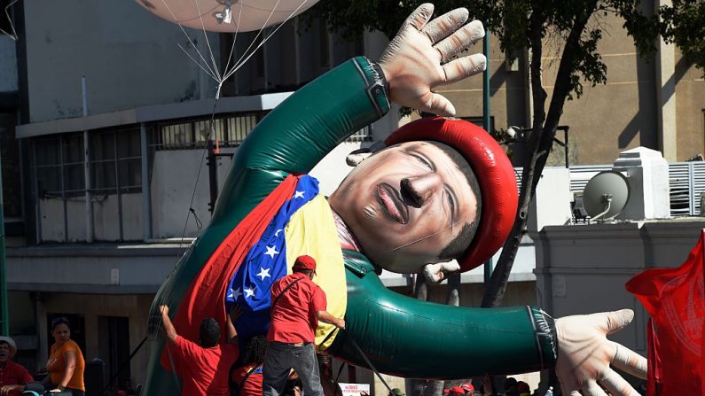 Un hombre ayuda a levantar un muñeco inflable que representa al difunto presidente Hugo Chávez durante un mitin de trabajadores de PDVSA frente al palacio presidencial de Miraflores en Caracas el 12 de enero de 2016. (JUAN BARRETO/AFP/Getty Images)
