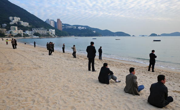 turistas chinos tomando fotos en la playa