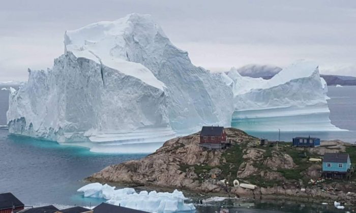 Un iceberg detrás de casas y construcciones en las afueras de la aldea de Innarsuit, un asentamiento insular en el municipio de Avannaata, en el noroeste de Groenlandia. (Magnus Kristensen/AFP/Getty Images)
