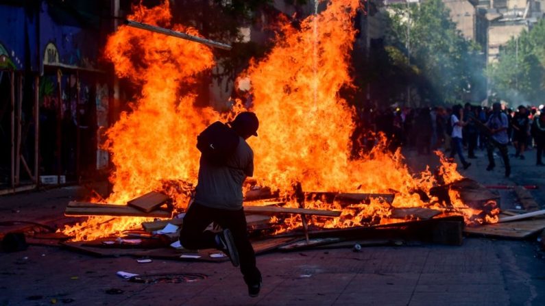 Manifestantes queimam uma barricada durante um protesto em Santiago, no Chile, em 21 de outubro de 2019. O número de mortos no Chile aumentou para 11, disseram autoridades na segunda-feira, após três dias de manifestações violentas e saques que fizeram com que o presidente Sebastián Piñera decretasse que o país estava "em estado de emergência"(Foto de MARTIN BERNETTI / AFP via Getty Images)