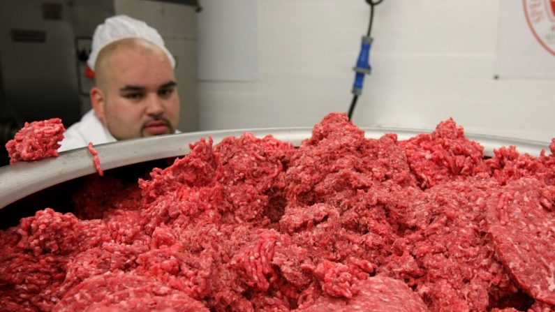 Foto de archivo que muestra a un trabajador en una instalación de envasado de carne que monitorea la carne molida cuando pasa a través de una máquina que hace hamburguesas (Justin Sullivan/Getty Images)