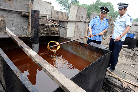 Policiais inspecionam um óleo de cozinha ilegal apreendido durante uma busca em Pequim, em 2 de agosto de 2010 (STR / AFP / Getty Images)