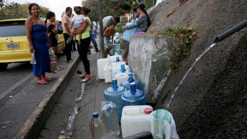 Moradores obtêm água de uma fonte natural da colina de El Ávila depois que o fornecimento de água foi suspenso após o blecaute nacional ocorrido em 10 de março de 2019 em Caracas, Venezuela (Edilzon Gamez / Getty Images)
