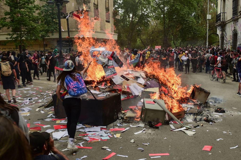 Los manifestantes queman documentos y objetos después de saquear una sucursal de un banco en Santiago el 25 de octubre de 2019, una semana después de que comenzara la violencia. (MARTIN BERNETTI / AFP / Getty Images)