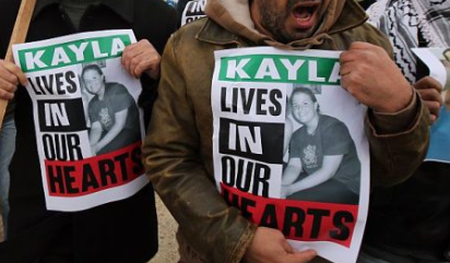 Manifestantes sostienen pancartas para protestar contra el "terrorismo" el 13 de febrero de 2015. Los carteles muestran imágenes de la cooperante estadounidense Kayla Mueller, que murió como rehén de los yihadistas del grupo Islamic State (ISIS). (ABBAS MOMANI/AFP vía Getty Images/ Fragmento de la imagen)