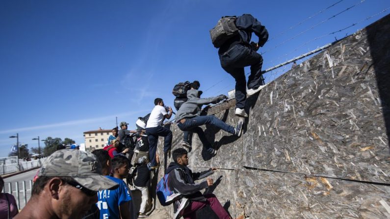 Un grupo de inmigrantes centroamericanos, principalmente de Honduras, cruzan una cerca mientras intentan llegar a la frontera entre Estados Unidos y México cerca del cruce fronterizo El Chaparral en Tijuana, Estado de Baja California, México, el 25 de noviembre de 2018. (PEDRO PARDO / AFP vía Getty Images)