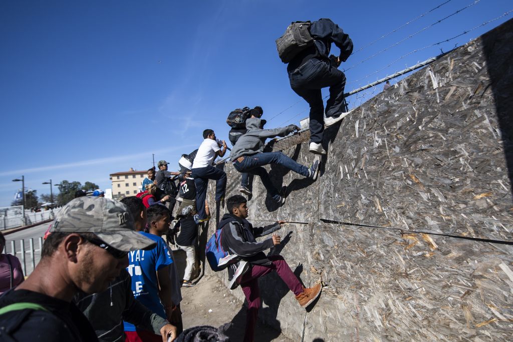 Un grupo de inmigrantes centroamericanos, principalmente de Honduras, cruzan una cerca mientras intentan llegar a la frontera entre Estados Unidos y México cerca del cruce fronterizo El Chaparral en Tijuana, Estado de Baja California, México, el 25 de noviembre de 2018. (PEDRO PARDO / AFP vía Getty Images)