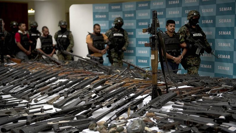 Marines mexicanos escoltan a cinco presuntos narcotraficantes del cártel de Zeta frente a un lanzacohetes RPG-7, granadas de mano, armas de fuego, cocaína y uniformes militares incautados a presuntos miembros del cártel de narcotraficantes Zetas y presentados a la prensa el 9 de junio de 2011 en la Secretaría de Marina en la Ciudad de México. (YURI CORTEZ/AFP via Getty Images)