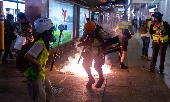 La reacción de los periodistas mientras la policía dispara gas lacrimógeno desde la estación del Metro de Causeway Bay durante unos enfrentamientos con manifestantes pro-democracia en Hong Kong, el 8 de septiembre de 2019. (Philip Fong/AFP/Getty Images)