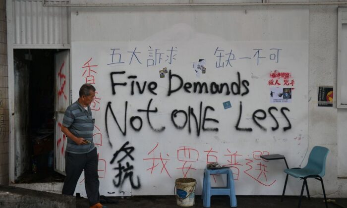 Un hombre sale de una puerta de una pared cubierta de graffiti en Hong Kong el 7 de octubre de 2019. (Nicolas Asfouri/AFP vía Getty Images)