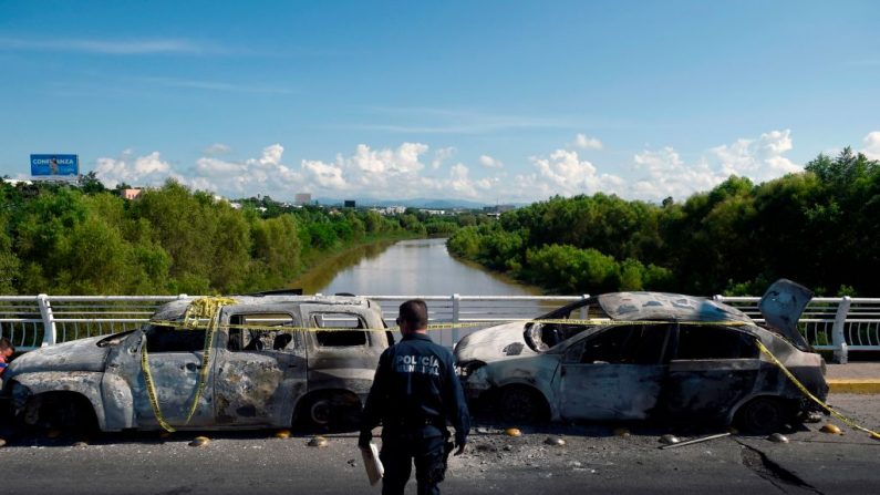 Un policía se para al lado de vehículos quemados después de que hombres armados flibraron una batalla en Culiacán, estado de Sinaloa, México, el 18 de octubre de 2019. Imagen de archivo.  (Alfredo Estrella/AFP vía Getty Images)