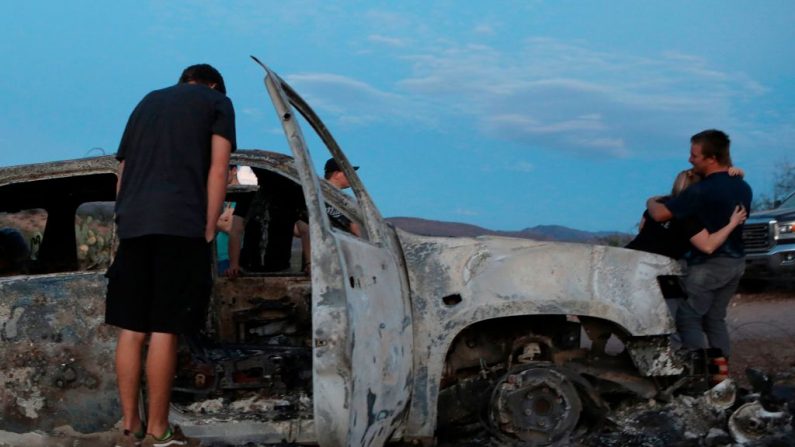 Miembros de la familia LeBaron miran el auto quemado donde parte de los nueve miembros asesinados de la familia fueron asesinados y quemados durante una emboscada en Bavispe, montañas de Sonora, México, el 5 de noviembre de 2019. (Foto de HERIKA MARTINEZ/AFP vía Getty Images)