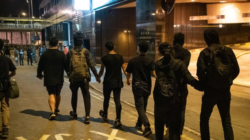 Manifestantes se toman de la mano mientras dejan la Universidad Politécnica de Hong Kong para entregarse a la policía, el 22 de noviembre de 2019. (Laurel Chor/Getty Images)