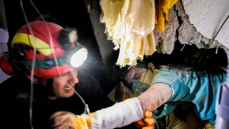  Un bombero intenta rescatar a un hombre atrapado en las ruinas de un edificio derrumbado en Thumane, al noroeste de la capital, Tirana, después de un terremoto en Albania, el 26 de noviembre de 2019. Armend Nimani / AFP a través de Getty Images)