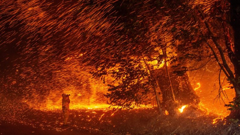 Un fotógrafo toma fotos en medio de una lluvia de brasas mientras el viento y las llamas se propagan por el área durante el incendio de Kincade cerca de Geyserville, California, el 24 de octubre de 2019. (Josh Edelson/AFP vía Getty Images)