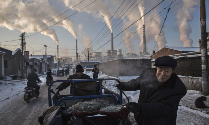 Columnas de humo salen de las chimeneas mientras hombres chinos tiran de un triciclo en un vecindario al lado de una planta de energía alimentada con carbón en Shanxi, China, el 26 de noviembre de 2015. (Kevin Frayer/Getty Images)

