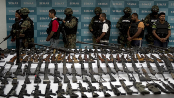 Fuzileiros navais mexicanos escoltam cinco suspeitos de tráfico de drogas do cartel Zetas em frente a granadas, armas, cocaína e uniformes militares apreendidos na Cidade do México em 9 de junho de 2011 (Yuri Cortez / AFP / Getty Images)