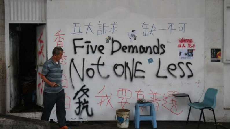 Un hombre pasa por una pared cubierta de graffiti en Hong Kong el 7 de octubre de 2019 (Nicolas Asfouri / AFP a través de Getty Images)