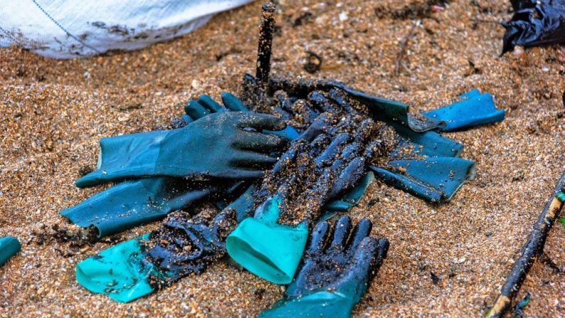 Luvas de proteção cobertas com óleo derramado na Praia de Busca Vida, em Camaçari, Bahia, Brasil, durante uma operação de limpeza em 3 de novembro de 2019 (Foto por MATEUS MORBECK / AFP via Getty Images)