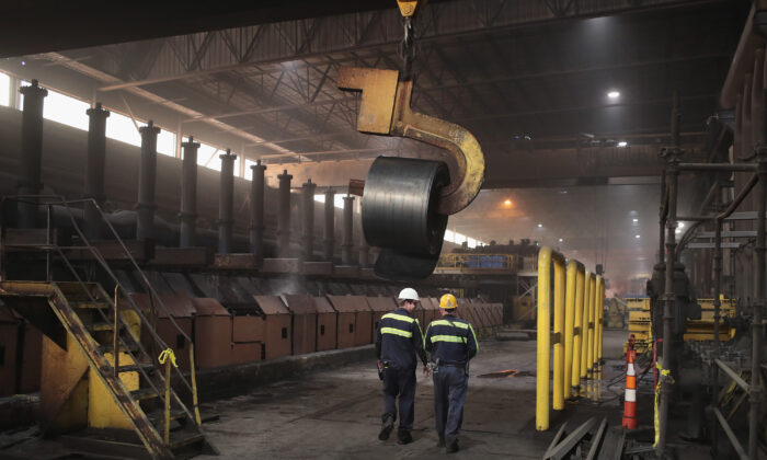 Los trabajadores retiran una bobina de la línea de producción para realizar pruebas de control de calidad durante la producción de acero en la fábrica de acero NLMK Indiana el 15 de marzo de 2018 en Portage, Indiana. (Scott Olson/Getty Images)