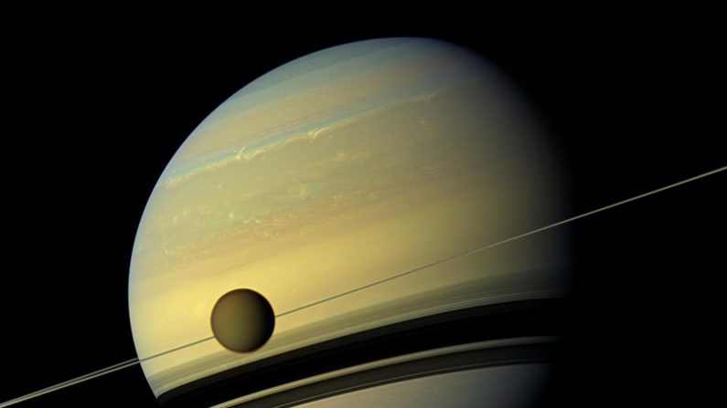 Una gigante luna Titan aparece ante el gigante planeta Saturno que está experimentando cambios estacionales en esta vista natural de color desde la nave espacial Cassini de la NASA. (NASA/JPL-Caltech/Space Science Institute)