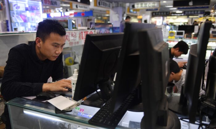 Un hombre repara un ordenador portátil en un centro comercial de Beijing, el 30 de marzo de 2018. (GREG BAKER/AFP vía Getty Images)