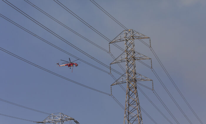 Un helicóptero pasa sobre las líneas eléctricas de PG&E durante las operaciones de extinción de incendios en Healdsburg, California, el 26 de octubre de 2019 (Philip Pacheco/AFP vía Getty Images)