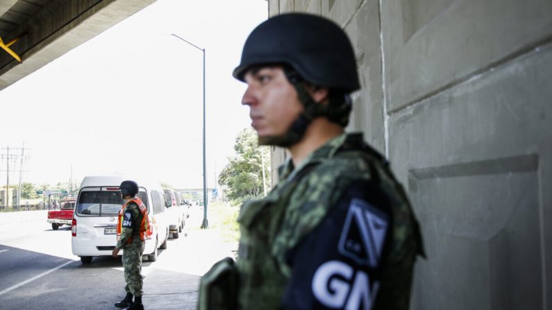 Miembros de la Guardia Nacional brindan seguridad en un puesto de control de carreteras para las autoridades de inmigración al sur de Tapachula, México, a 25 millas al norte de la frontera del río Suchiate con Guatemala, el 28 de junio de 2019. (Charlotte Cuthbertson/The Epoch Times)