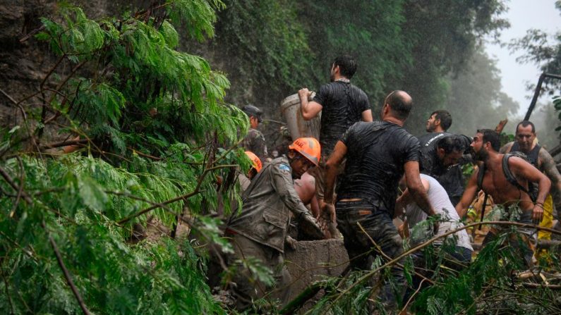 Bomberos, trabajadores municipales, policías y voluntarios participan en una operación de rescate después de un deslizamiento de tierra causado por las fuertes lluvias en Río de Janeiro, Brasil, el 9 de abril de 2019. (MAURO PIMENTEL/AFP/Getty Images)