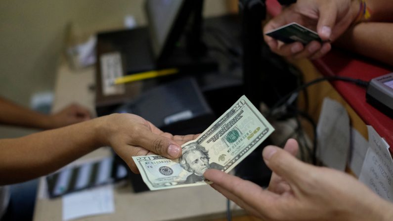 Un cliente paga con un billete de veinte dólares en una panadería el 26 de junio de 2019 en Caracas, Venezuela. (Matias Delacroix / Getty Images)