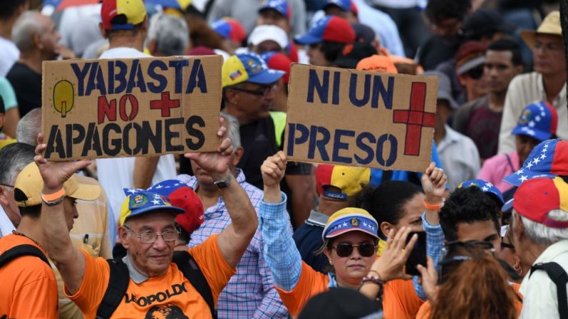 La gente sostiene carteles que decían "Basta de apagones" y "Ni un prisionero más" antes de una sesión de la Asamblea Nacional liderada por la oposición en la plaza Alfredo Sadel en Caracas el 23 de julio de 2019. (YURI CORTEZ/AFP/Getty Images)