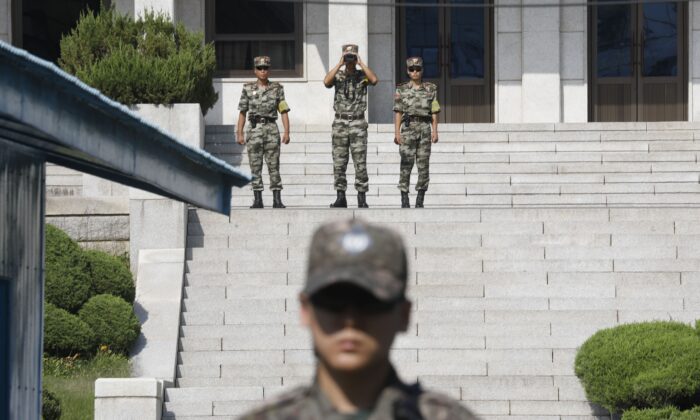 Los soldados norcoreanos (arriba) miran hacia el sur mientras un soldado surcoreano (abajo) hace guardia en la aldea de tregua de Panmunjom dentro de la Zona Desmilitarizada (DMZ) que separa a las dos Coreas el 28 de agosto de 2019. (KIM HONG-JI / AFP a través de Getty Images)