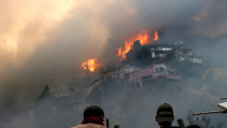 Los hombres miran las casas en llamas durante un incendio forestal en la colina Rocuant en Valparaíso, Chile, el 24 de diciembre de 2019. (RAUL ZAMORA / ATON CHILE / AFP a través de Getty Images)