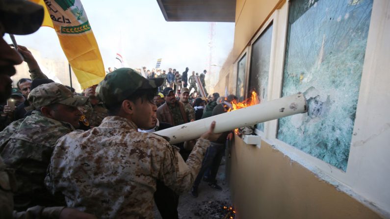 Un grupo utiliza un tubo de plomería para romper los cristales a prueba de balas de las ventanas de la embajada estadounidense en Bagdad, el 31 de diciembre de 2019. (Foto de AHMAD AL-RUBAYE/AFP vía Getty Images)