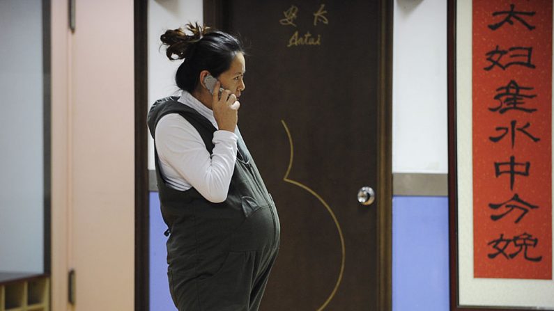 Esta imagen tomada el 28 de noviembre de 2012 muestra a una mujer embarazada hablando por un teléfono móvil frente a una sala de parto en el Hospital Antai en Beijing. (WANG ZHAO/AFP/Getty Images)