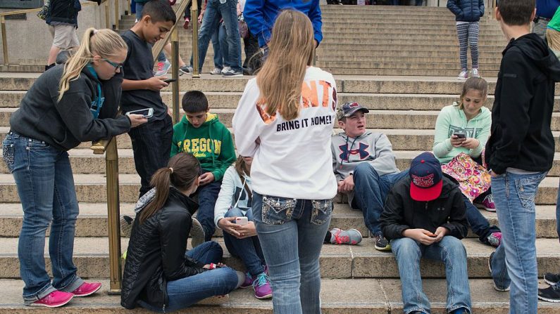 Un grupo de adolescentes revisa sus teléfonos inteligentes afuera del Museo de Historia Natural en Washington el 8 de abril de 2015. (NICHOLAS KAMM/AFP a través de Getty Images)