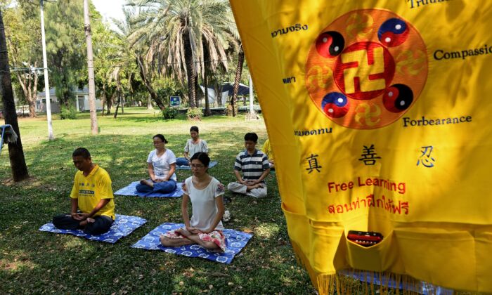 Practicantes chinos de Falun Dafa y solicitantes de asilo meditando en Bangkok el 14 de marzo de 2016. (LILLIAN SUWANRUMPHA/AFP vía Getty Images)