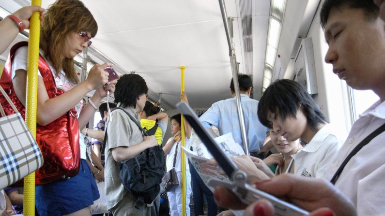 Usuarios revisan su teléfono móvil en una línea de metro de Beijing, el 19 de julio de 2007. (FREDERIC J. BROWN / AFP / Getty Images)