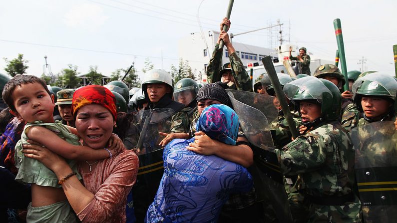 Policías chinos empujan a mujeres uigures que protestaban en una calle el 7 de julio de 2009, en Xinjiang, China. (Guang Niu/Getty Images)