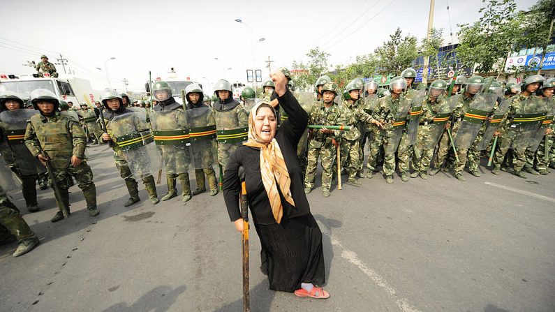 La policía antidisturbios china observa a una mujer musulmana de etnia uigur protestar en Urumqi, en la provincia de Xinjiang, en el extremo oeste de China. (PETER PARKS/Getty Images)
